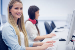 student sitting behind computer smiling at camera