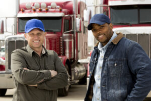 two truck drivers standing in front of two semi trucks