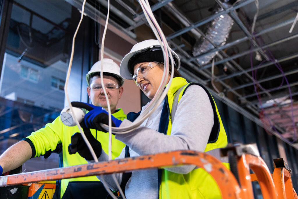 electrician teaching apprentice to work on electrical system